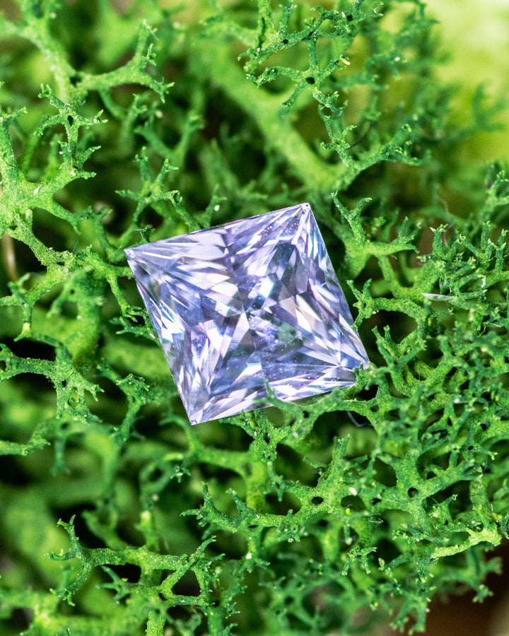 2.15 carat lilac gray lavender sapphire displayed on bright green moss, capturing natural light reflections through the custom kite cut facets, untreated gemstone from Sakaraha, Madagascar.