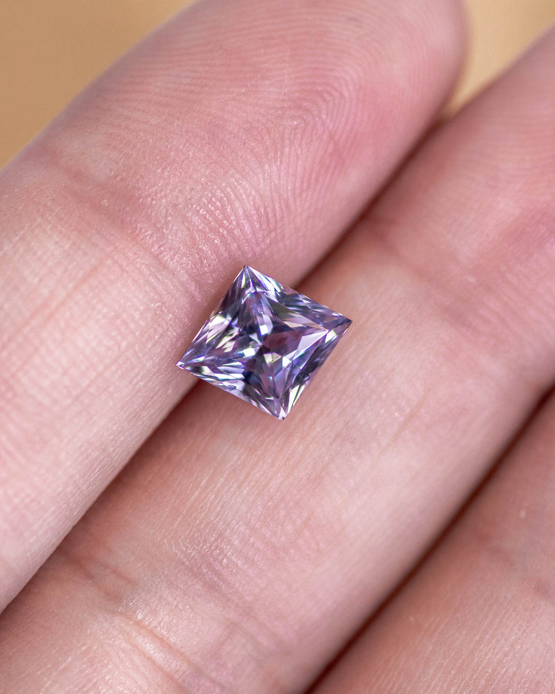 2.15 carat gray lilac lavender sapphire resting on fingertip, showing the precision of its custom kite cut and soft reflective pastel tones, untreated gemstone from Sakaraha, Madagascar.