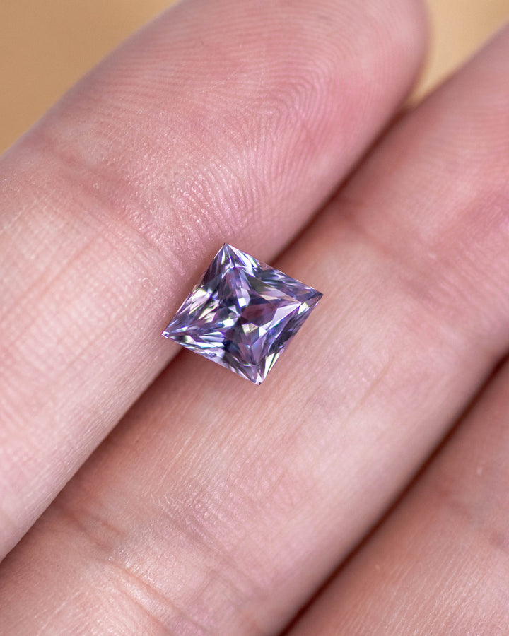 2.15 carat gray lilac lavender sapphire resting on fingertip, showing the precision of its custom kite cut and soft reflective pastel tones, untreated gemstone from Sakaraha, Madagascar.