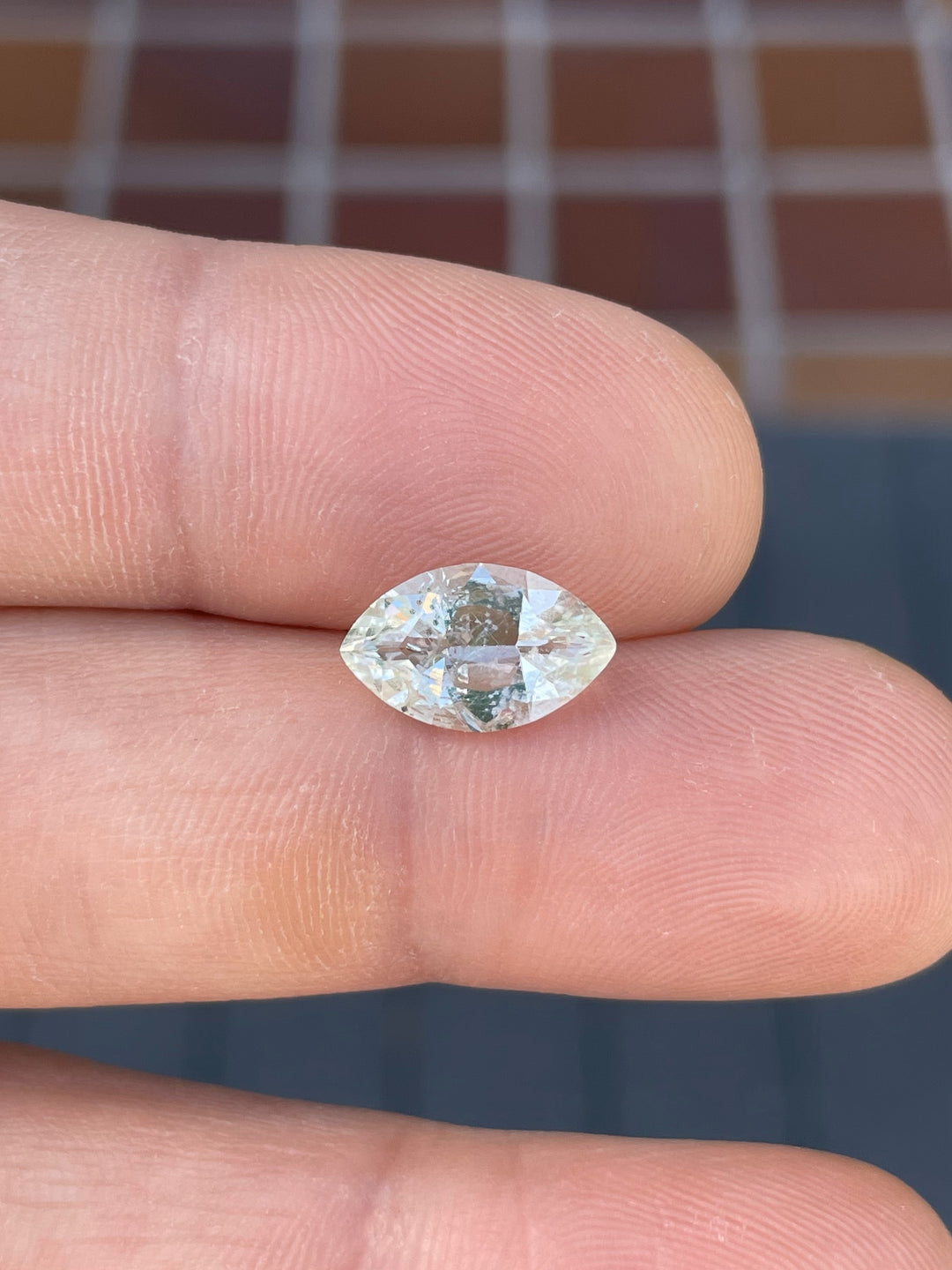 A stunning 2.18-carat Hyalite Opal held between fingers, showcasing its colorless clarity with green and blue hues.
