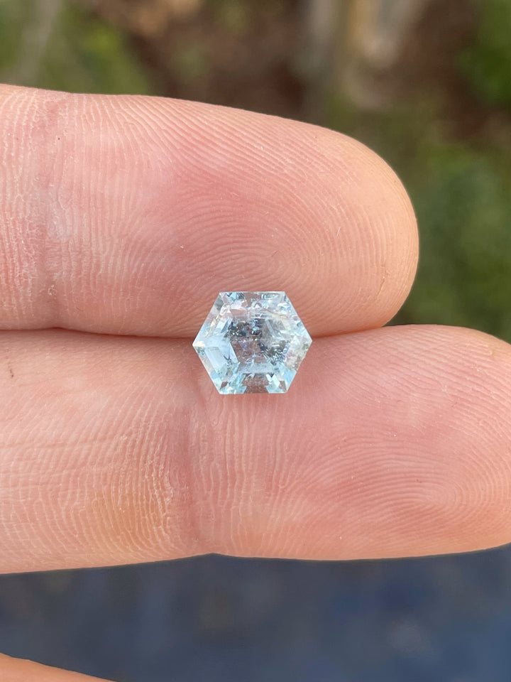 A rare 2.20ct Green Beryl in a hexagon step cut, delicately placed on fingertips, showcasing its light blue-green hues.