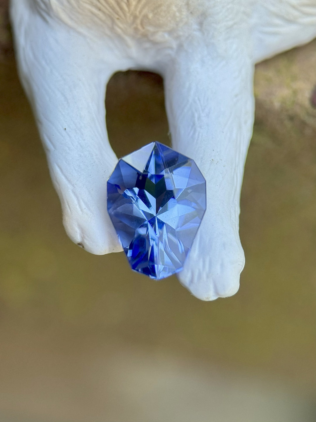 Ultra Violet Blue Tanzanite displayed on a ceramic figure, showcasing its custom shield cut brilliance and vivid untreated color.