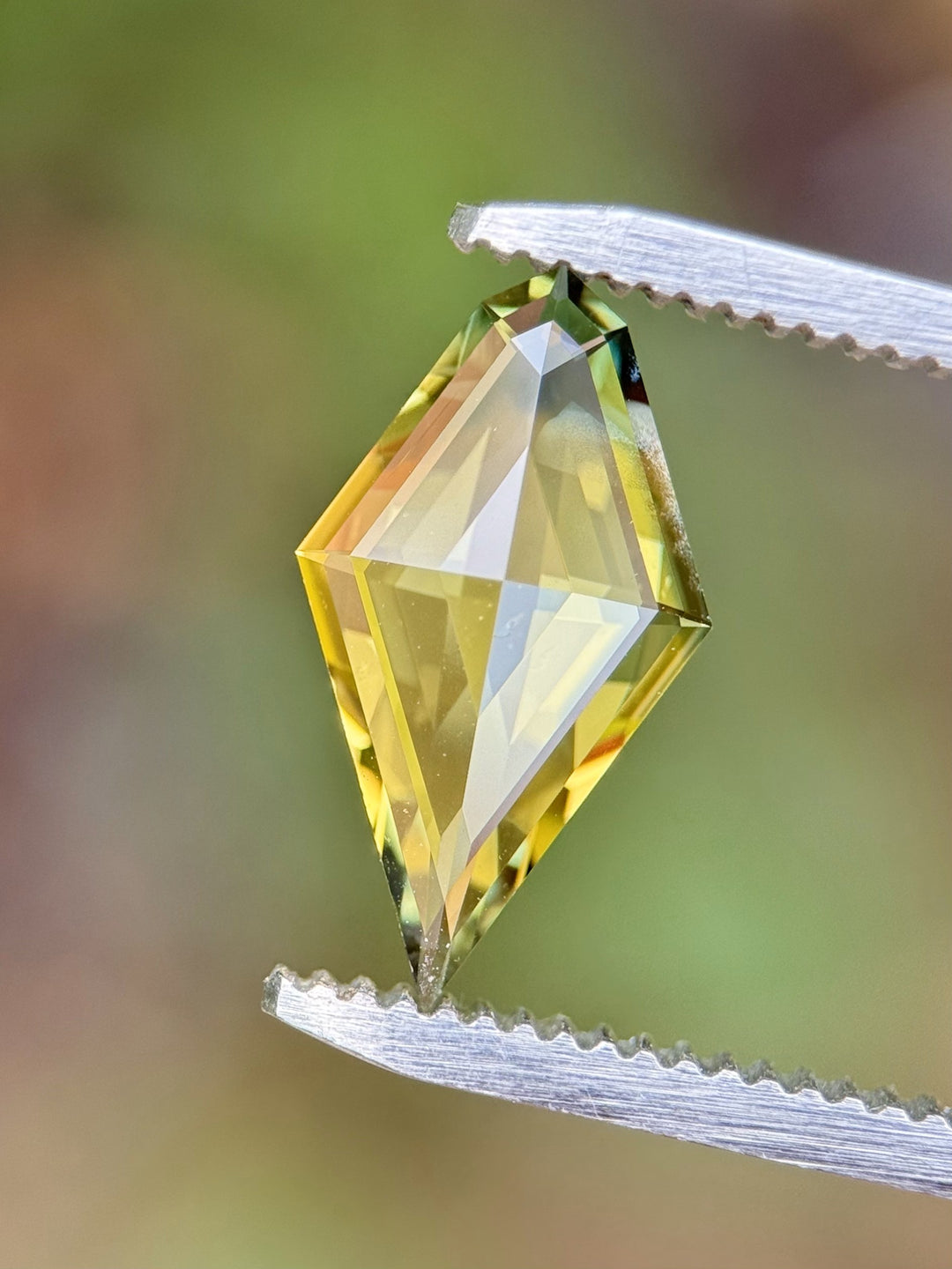 Close-up view of a precision-cut 2.38-carat kite-shaped parti sapphire with yellow and blue hues, ethically sourced from Kenya.