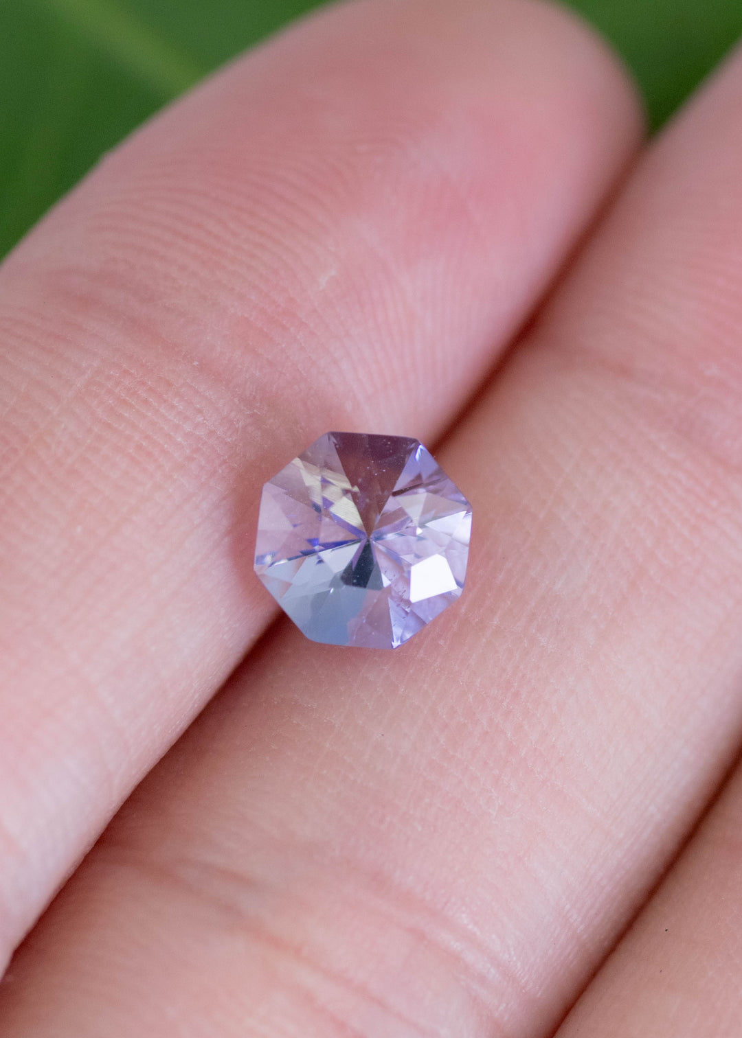 2.38 carat periwinkle violet Tanzanite custom mix brilliant octagon resting on finger, precision faceted gemstone from Merelani Hills Tanzania showing sparkle, symmetry and vibrant color for custom jewelry