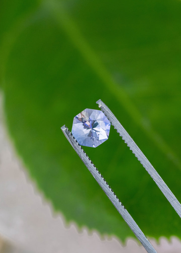 2.38 carat periwinkle violet Tanzanite mix brilliant octagon held in tweezers, precision faceted gemstone from Merelani Hills Arusha Tanzania displaying clarity, brilliance and designer cut for fine jewelry
