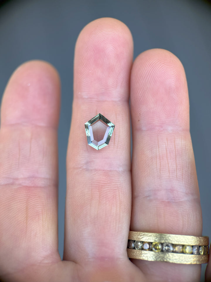 2.50 carat Montana sapphire in custom shield cut showing color change, displayed on hand for scale