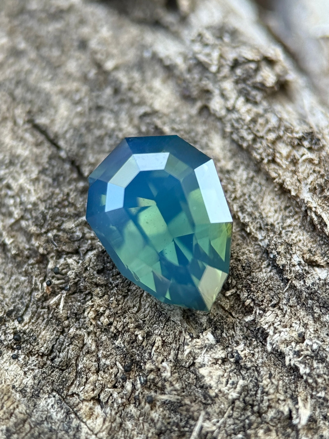2.51 carat opalescent teal blue green sapphire shown face-up, displaying precision shield step cut faceting and luminous oceanic color from Diego, Madagascar.