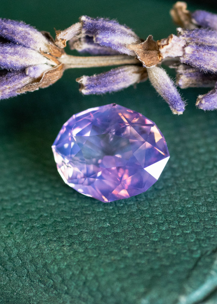 Loose 2.52 carat opalescent purple pink sapphire from Ratnapura shown face-up, displaying the precision oval mix cut and luminous pastel glow.