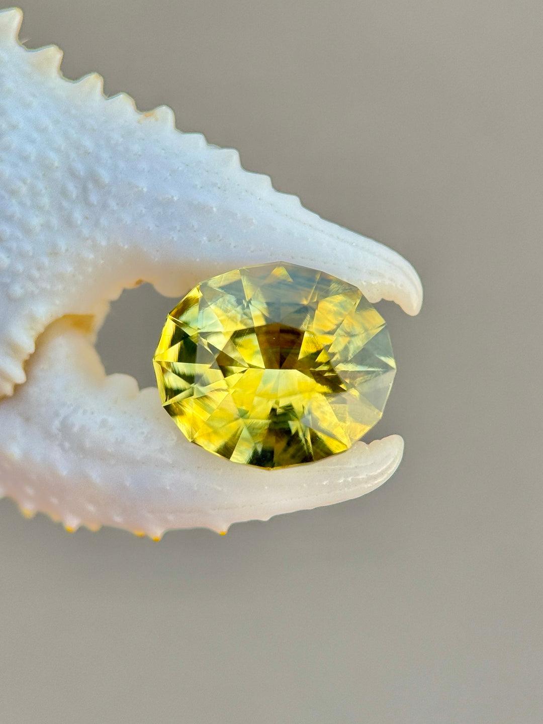 2.52 carat parti yellowish green sapphire shown face-up, displaying modified oval mix cut faceting and natural green-gold color zoning from Sakaraha, Madagascar.