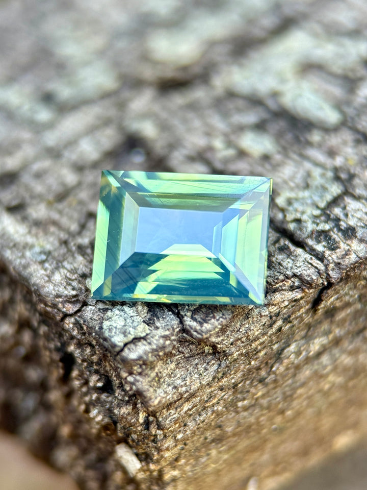 2.53 carat opalescent teal blue green sapphire shown face-up, displaying precision baguette step cut faceting and luminous color from Diego, Madagascar.
