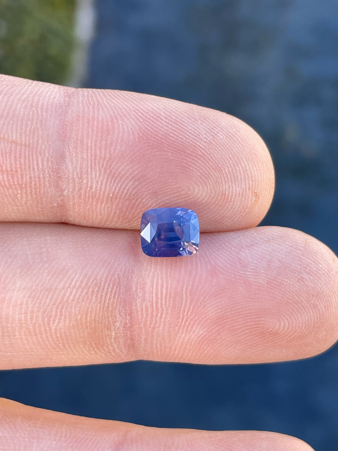 A stunning 2.56-carat cushion-cut sapphire in a mauve, pink, and purple opalescent hue, sourced from Tanzania and untreated.