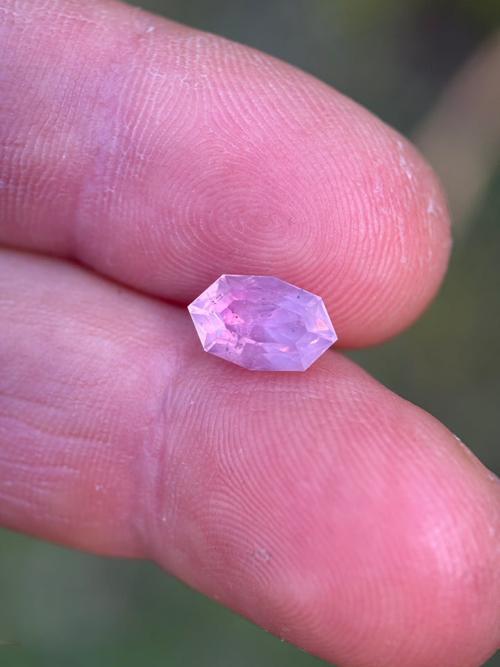 Opalescent sapphire on fingertip showing size scale and soft diffused color.