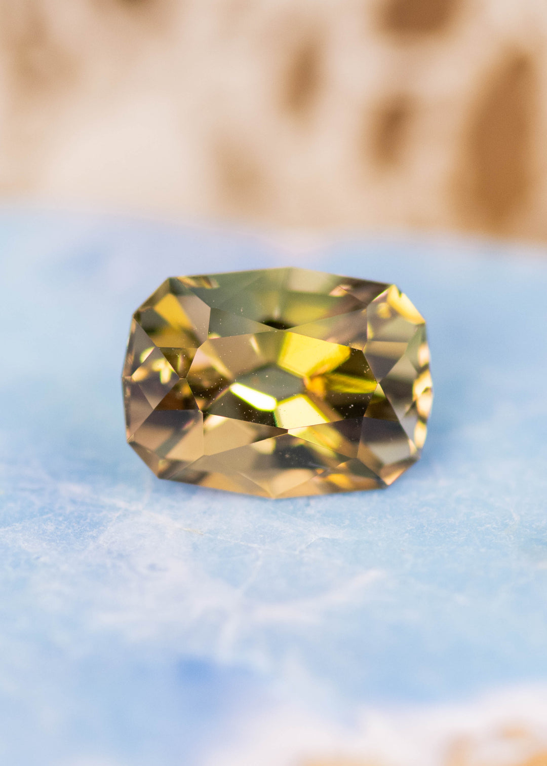 2.59 carat green yellow Tanzanite custom geometric cushion cut placed on display surface, untreated gemstone from Merelani Hills Tanzania highlighting natural color variation and precision cut facets