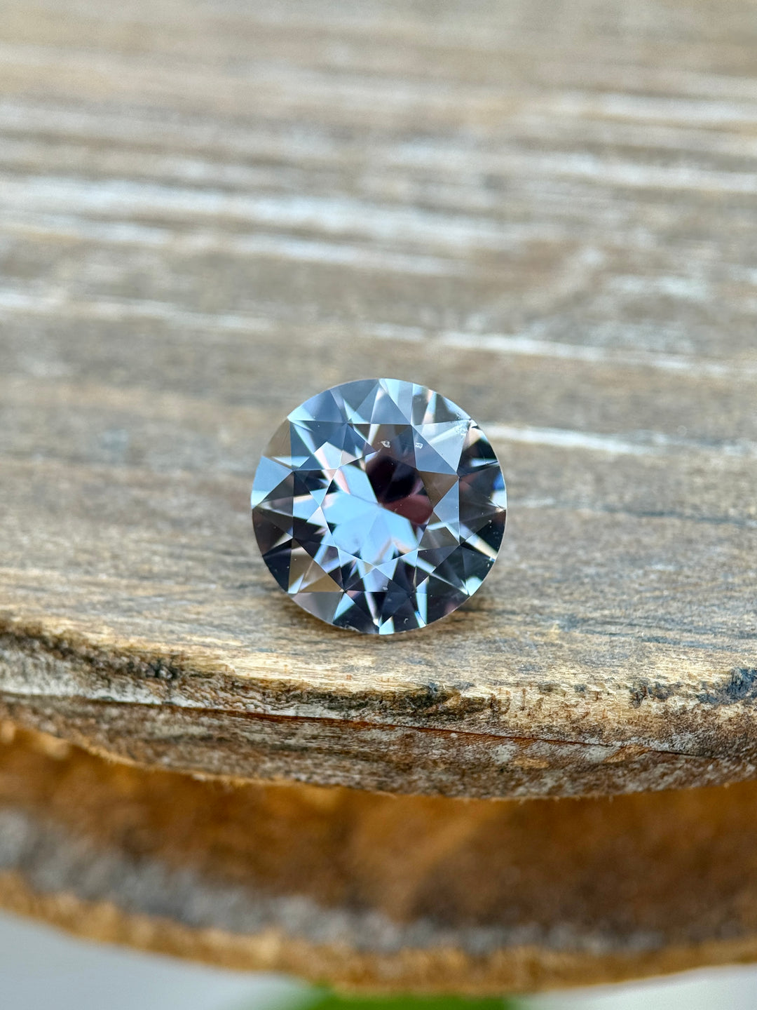 2.60CT color-changing sapphire photographed on a rustic wooden surface, showing grey and steely violet hues in a precision antique transitional round cut from Sakaraha, Madagascar.