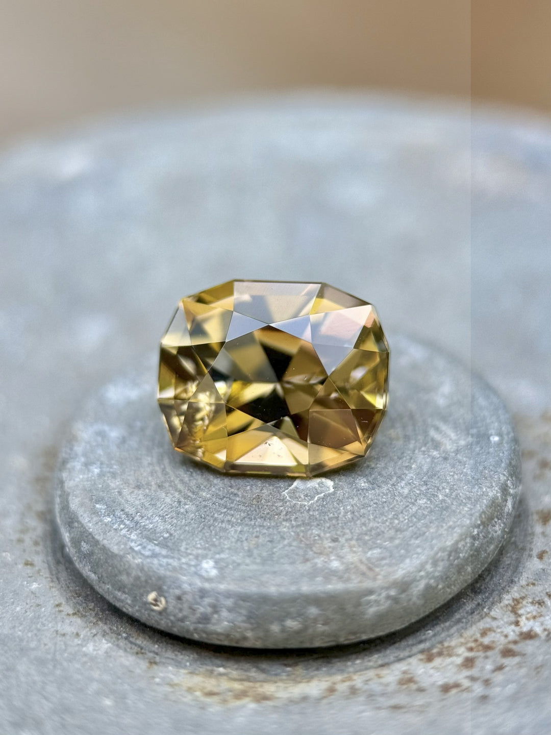 Golden yellow Tanzanite gemstone in custom geometric cushion shape resting on a stone surface – 2.60 carats, untreated gem from Merelani Hills, Tanzania
