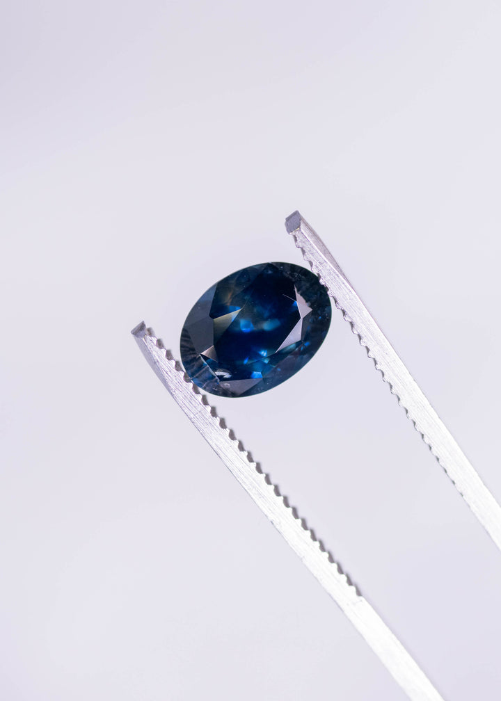 2.62ct heated blue Montana sapphire oval mix cut held in gem tweezers, showcasing brilliance, deep blue saturation and oval faceting from El Dorado Bar Deposit