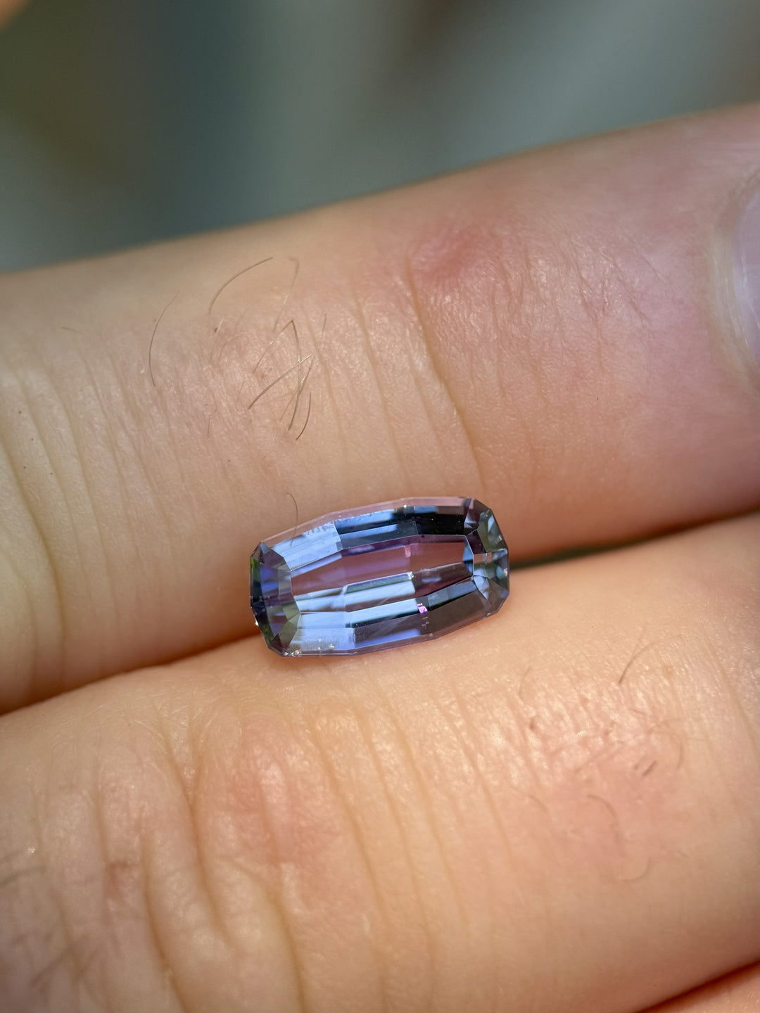 2.63-carat Tanzanite on finger showcasing untreated multicolor hues in modified emerald cut, from Merelani Hills, Tanzania