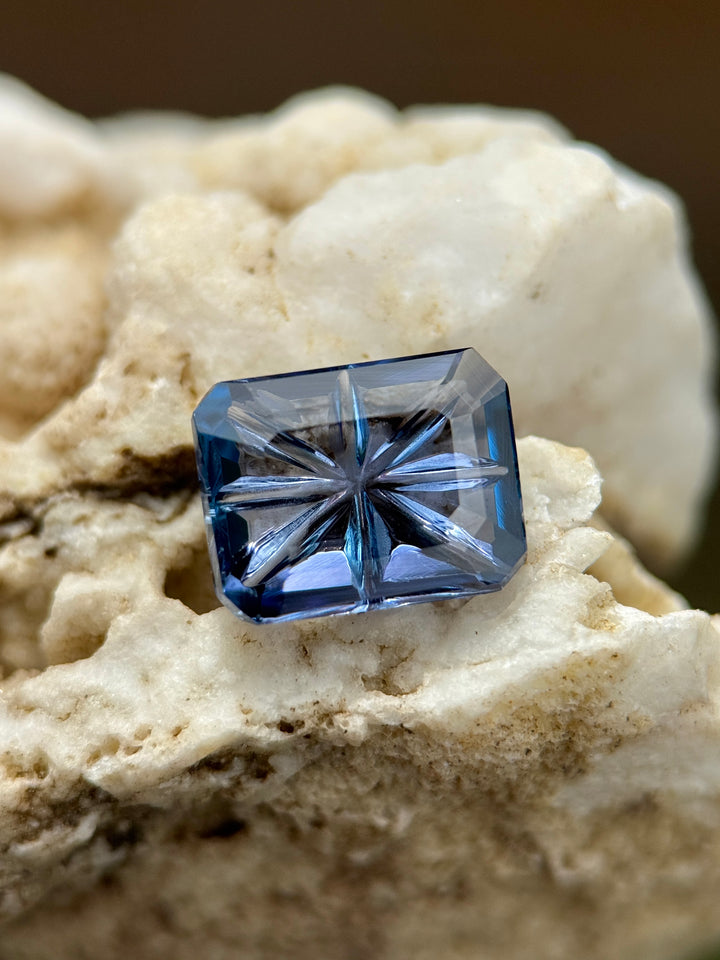 2.99 carat violet, teal, and blue Tanzanite in an octagonal concave portrait cut from Merelani Hills displayed on natural stone, showcasing the starburst concave pattern and untreated clarity.