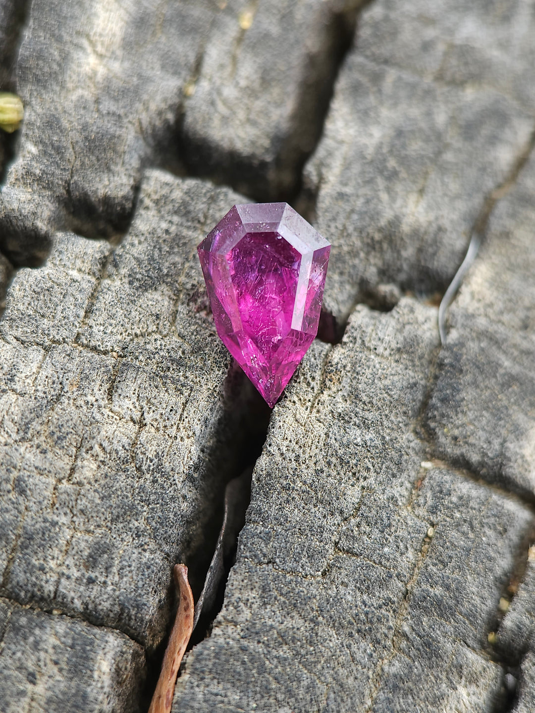 Garnet gemstone set in the crevice of a gray, textured rock, highlighting its rich purple hue and precision cut, emphasizing its natural origin from Kenya with no treatments.