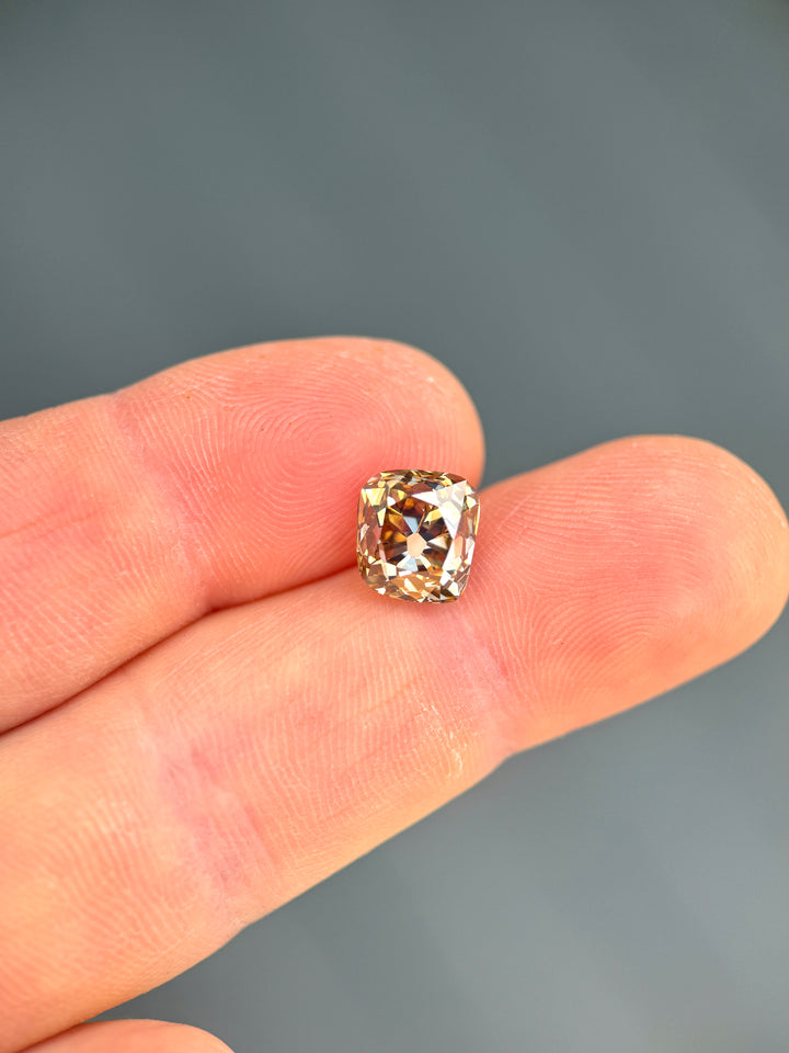 Close-up of a 3.93 carat Canadian champagne diamond on fingertips, highlighting its antique cushion shape, VVS1 clarity, and warm brown-gold brilliance.