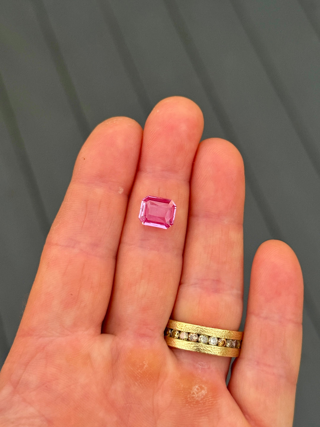 Close-up of 3.01 carat pink sapphire resting on the palm of a hand, revealing vivid pink saturation and reflective depth of the custom octagonal portrait cut, untreated sapphire from Sakaraha, Madagascar.