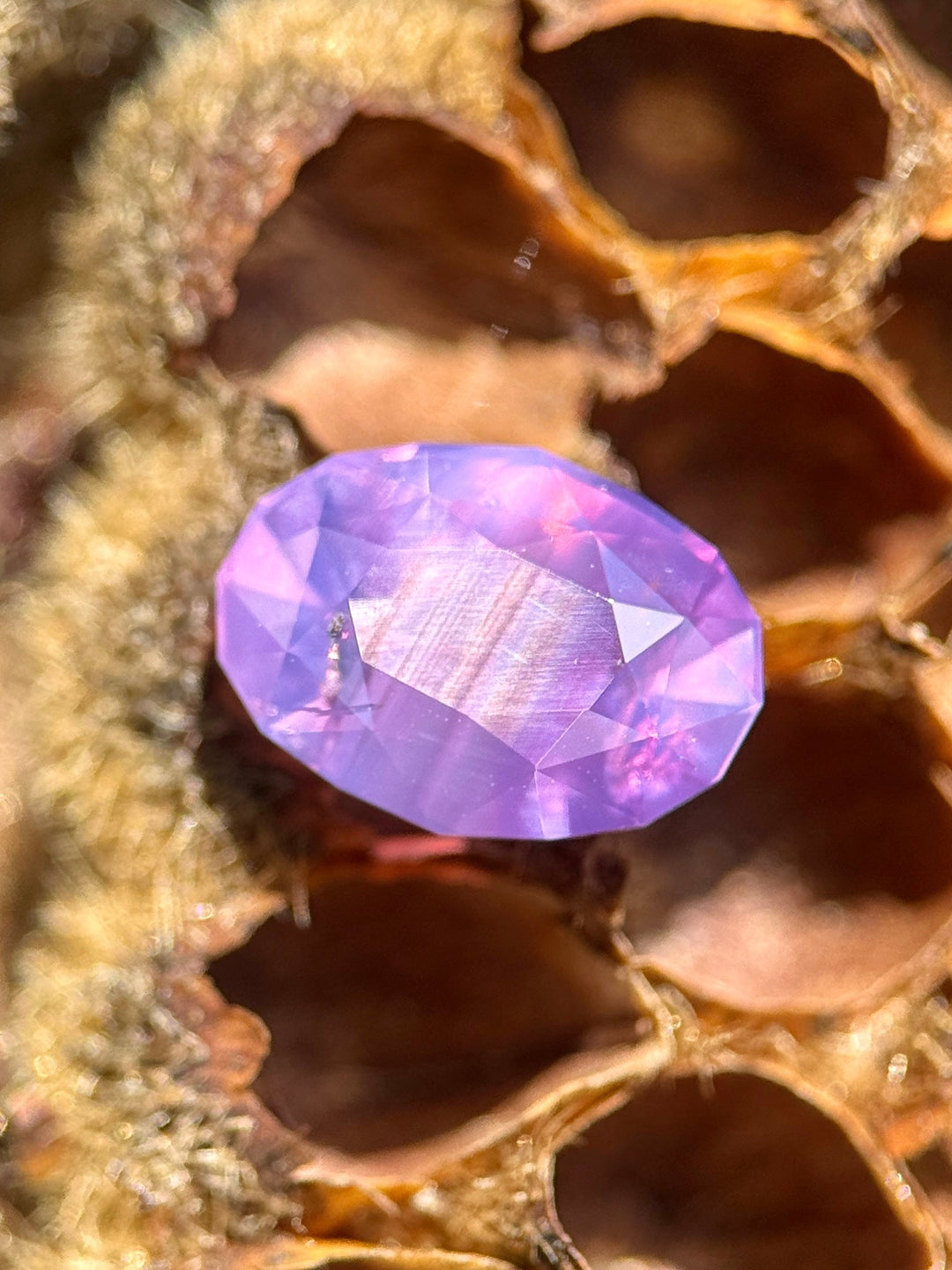 3.01 carat opalescent purplish pink sapphire shown face-up, displaying modified oval brilliant mix cut faceting and luminous pastel color from Sakaraha, Madagascar.