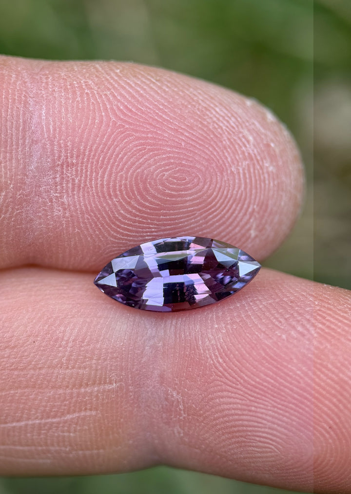 3.06 carat pink and purple sapphire in marquise brilliant cut, shown on fingertip to display color saturation and clarity, ethically sourced from Sakaraha, Madagascar.
