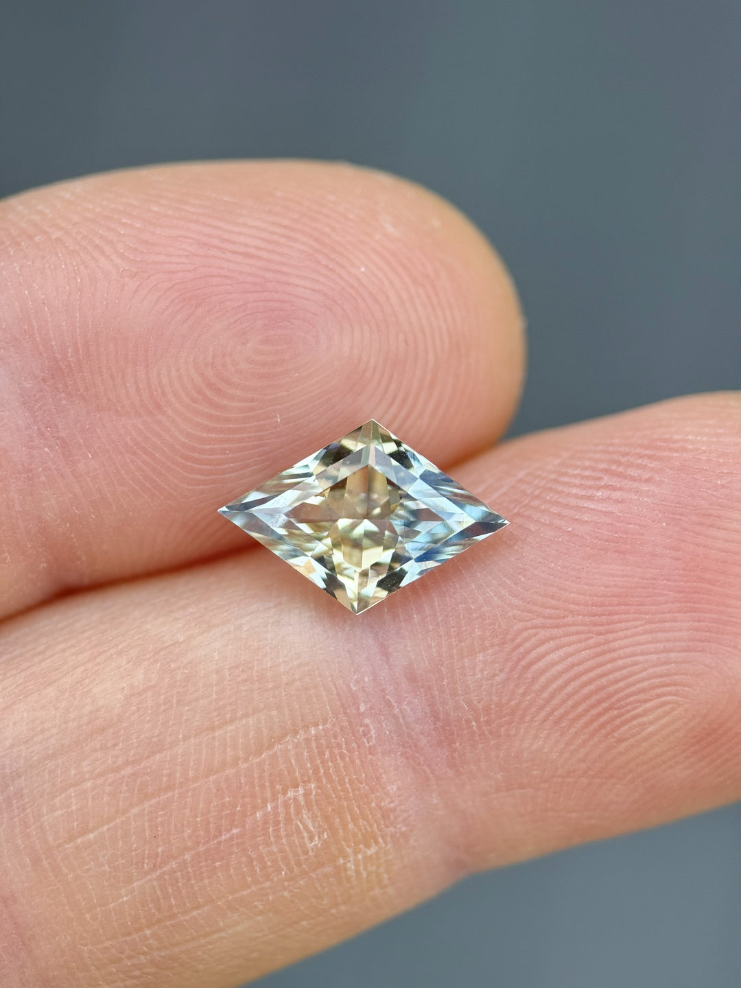 3.07ct lozenge mixed cut parti sapphire resting on fingertip, revealing its vivid untreated yellow and blue coloration