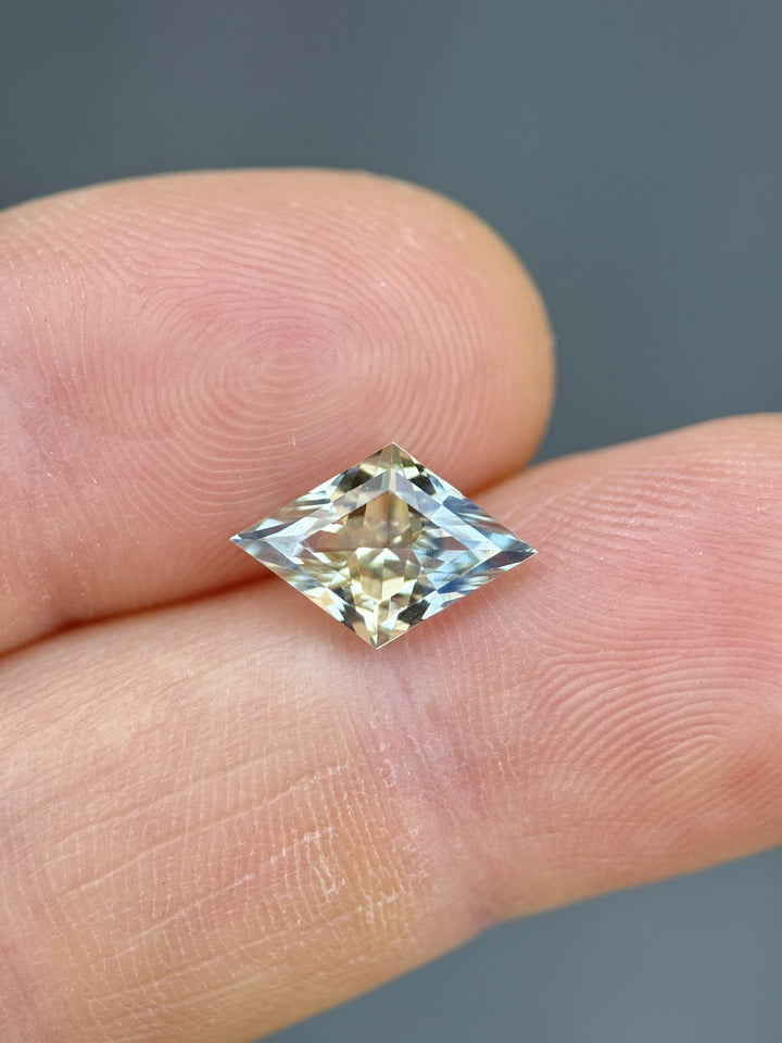 3.07ct lozenge mixed cut parti sapphire resting on fingertip, revealing its vivid untreated yellow and blue coloration