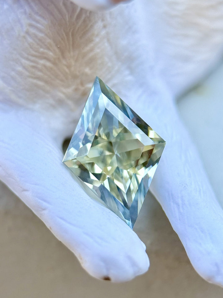 Close-up of a 3.07ct custom lozenge cut sapphire with parti yellow and blue colors, displayed on a ceramic cat figurine