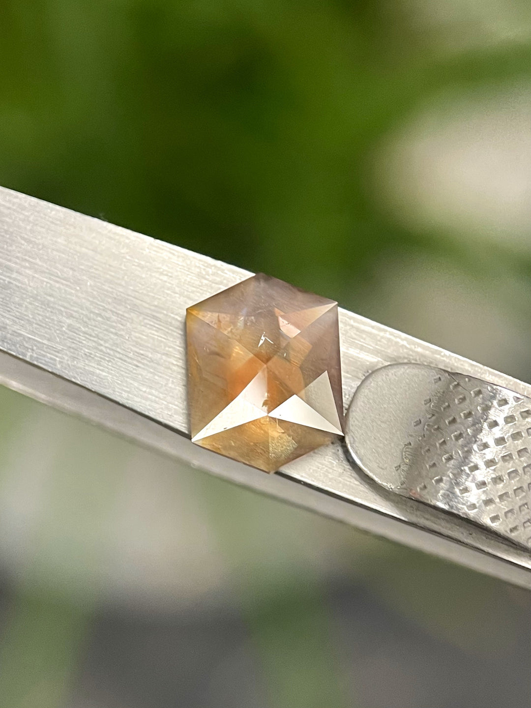 A stunning 3.12 carat amber sapphire showcasing shades of orange, mauve, and brown in a custom hexagon rose cut. Originating from the Umba River, Tanzania, this untreated gem features intricate facets and natural brilliance.