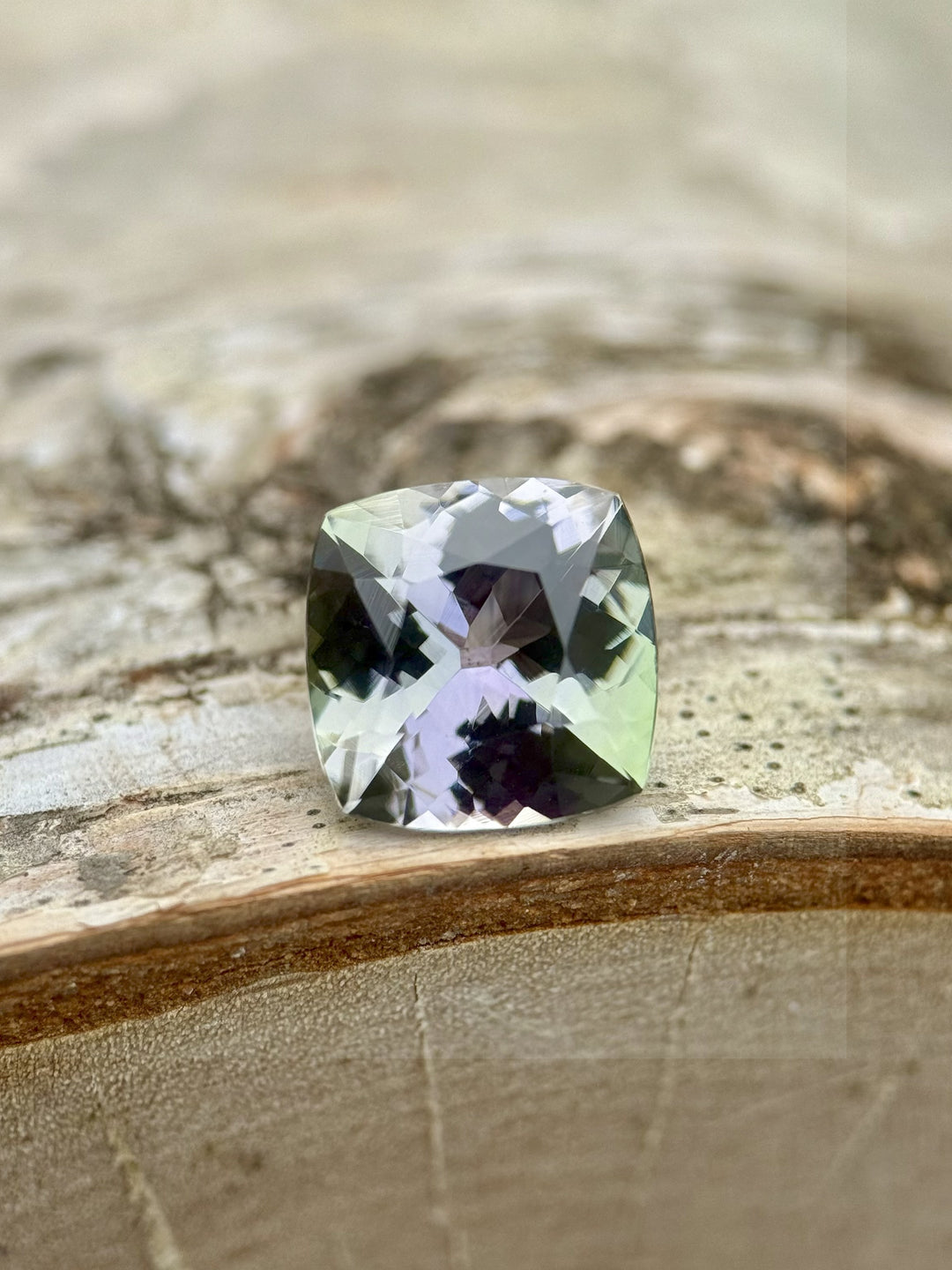 3.13 carat green and purple cushion cut Tanzanite on wood background – untreated gemstone from Merelani Hills, Tanzania