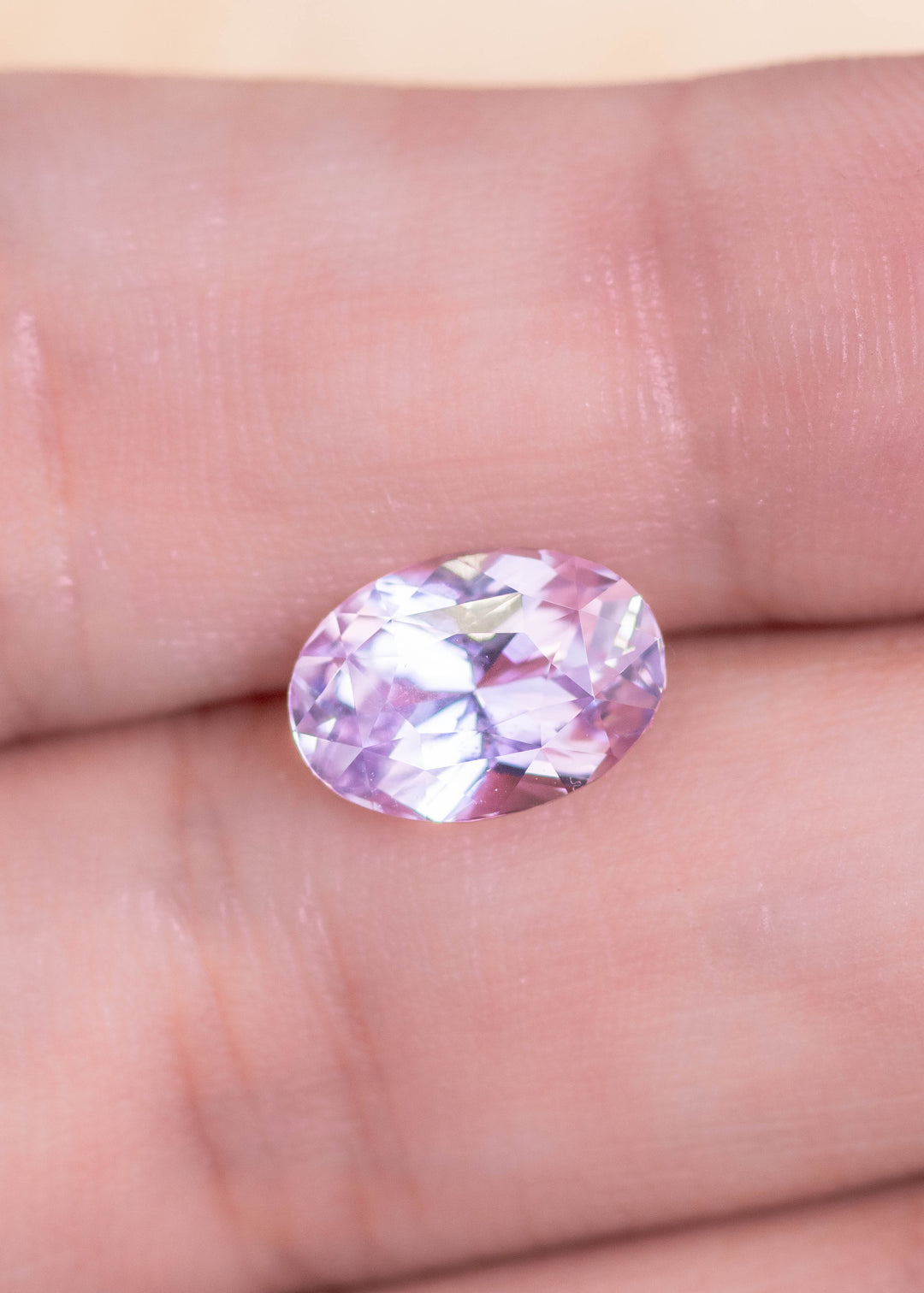 Loose lavender pink purple sapphire from Sakaraha Madagascar held in tweezers showing the brilliance and facet pattern of the precision oval mixed cut.
