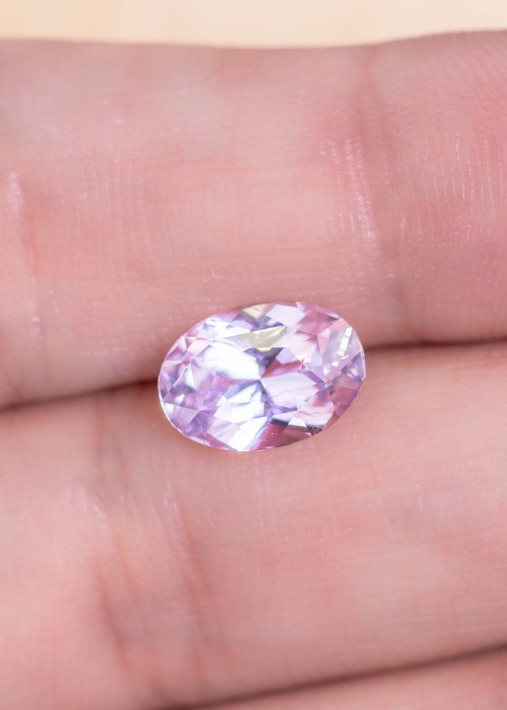 Loose lavender pink purple sapphire from Sakaraha Madagascar held in tweezers showing the brilliance and facet pattern of the precision oval mixed cut.