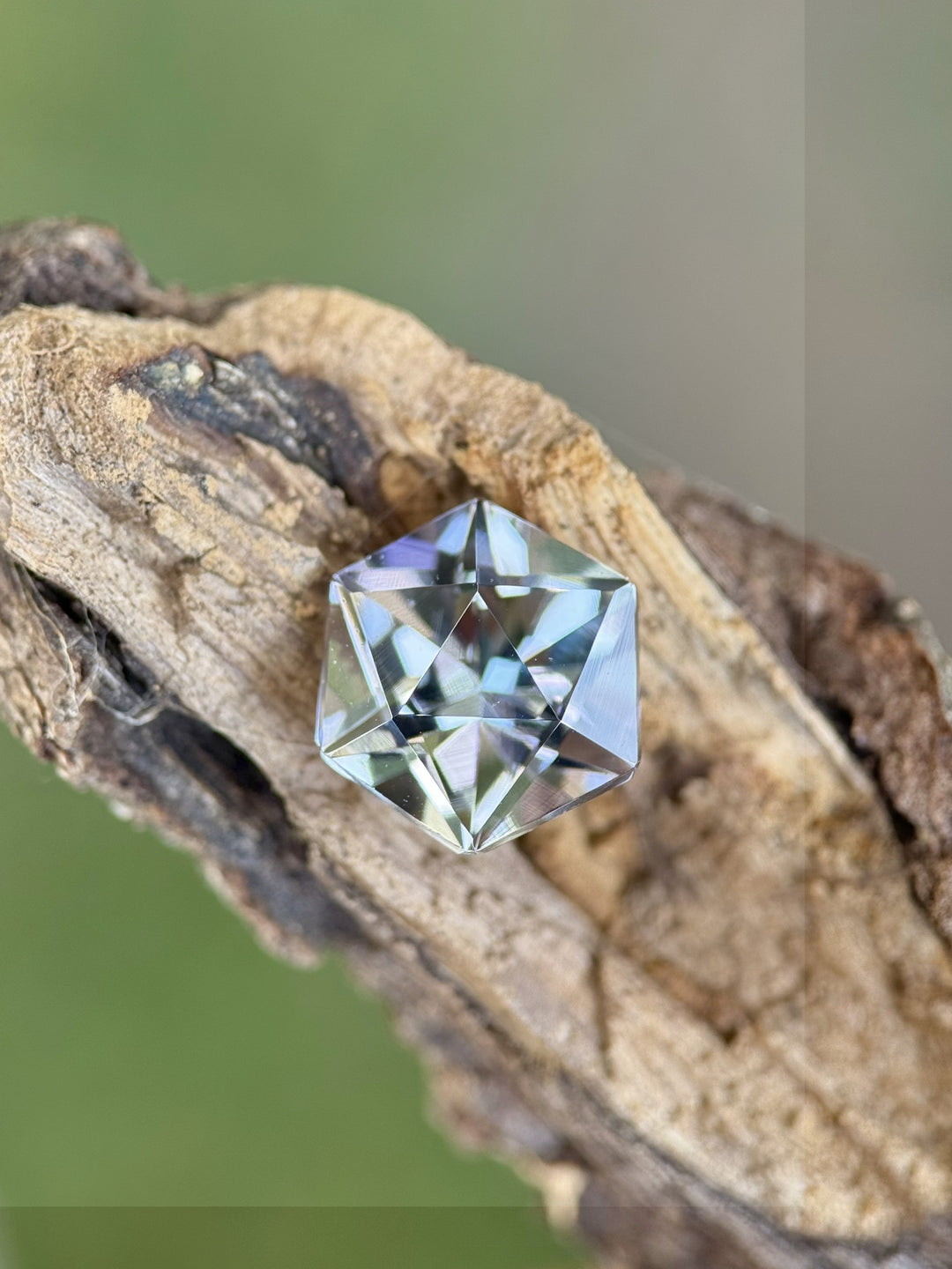Untreated 3.32ct Tanzanite with custom hexagonal mix cut showing lavender, teal, and green hues resting on natural driftwood.