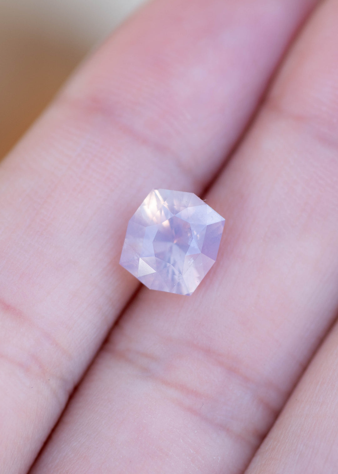 Loose 3.43 carat opalescent lavender pink sapphire shown on hand displaying size, soft glow, and geometric radiant cut.