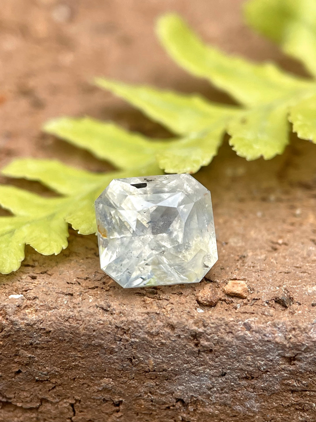 Custom radiant-cut sapphire gemstone in earthy pale yellow, gray, and blue colors, weighing 3.60 carats.