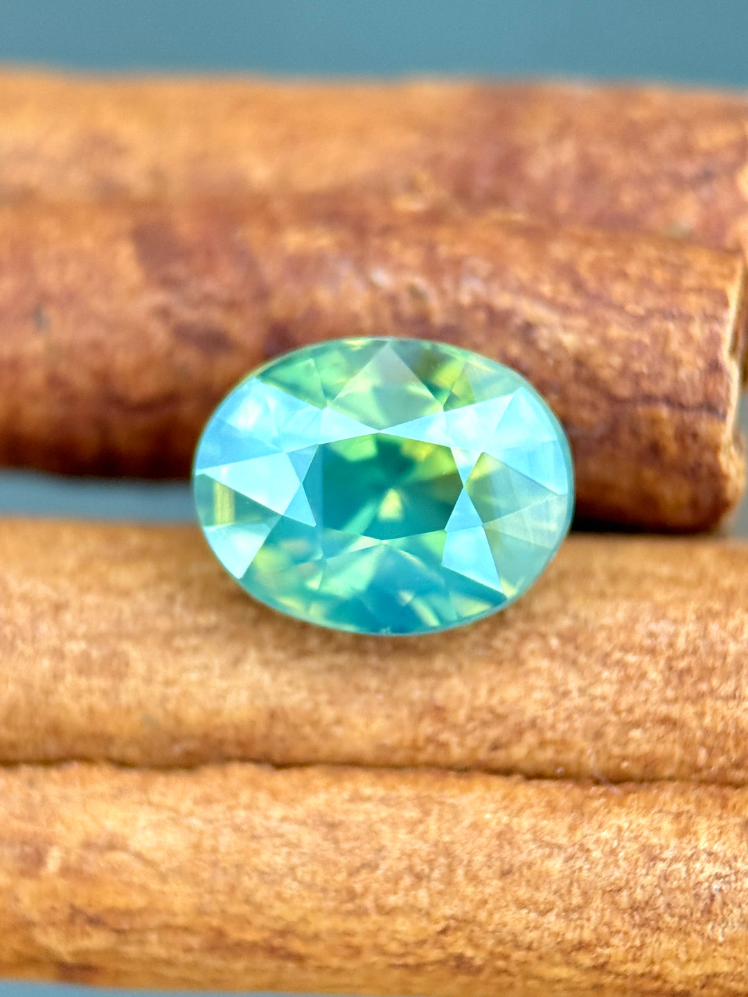 3.60 carat opalescent teal blue green parti sapphire shown face-up, displaying precision oval mixed cut faceting and vivid natural color zoning from Diego, Madagascar.