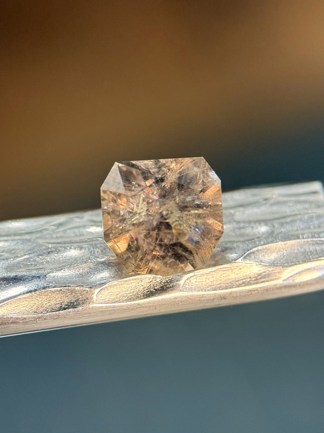 Side profile of a custom calf head cut earthy grey-green 3.82 carat sapphire, showing intricate inclusions and color transition.