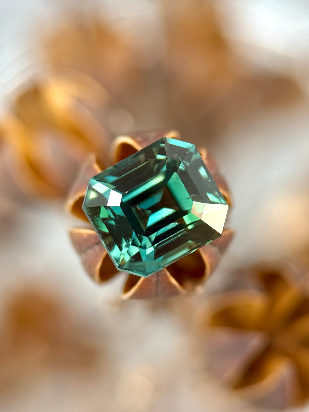 Loose vivid blue green sapphire from Madagascar shown face-up displaying the precision emerald cut and deep saturated color.