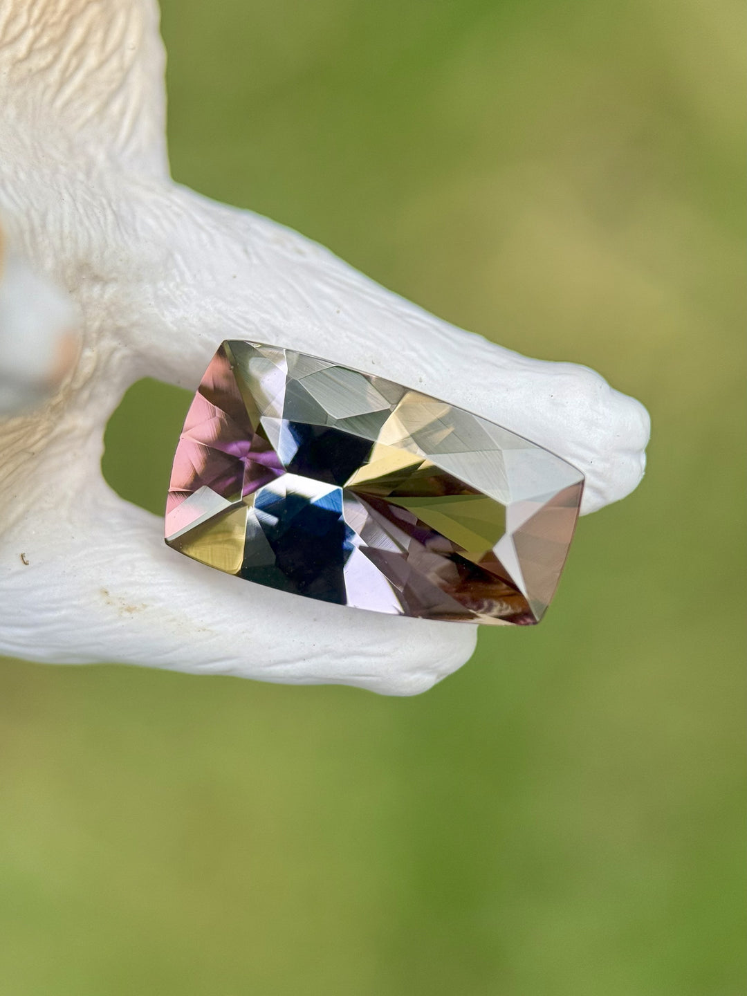 4.35 carat untreated Tanzanite in custom elongated tapered cushion cut, displaying yellow, teal, lavender, and red tones, shown resting on antler background