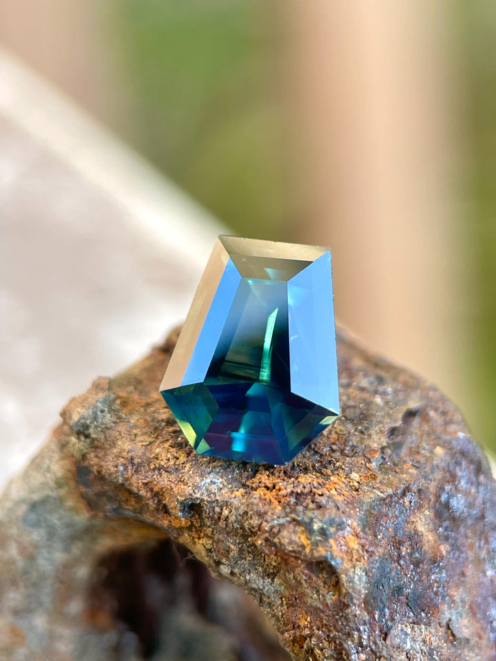 4.65 carat forest green, teal, and yellow sapphire from Gombe, Nigeria. Step cut coffin shaped gemstone measuring 10.92 x 8.88 x 5.90 mm, untreated and priced at $5580.00.