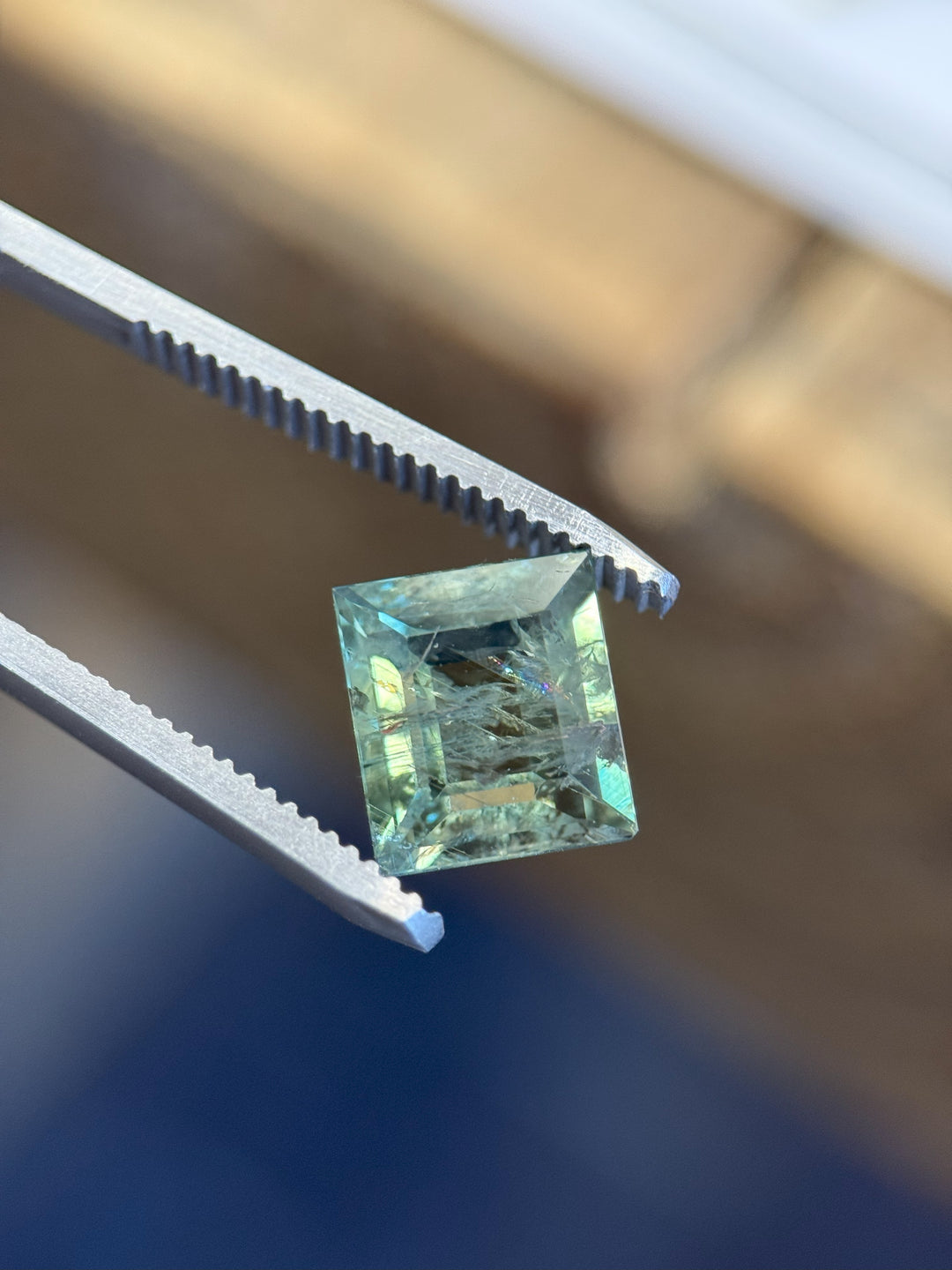4.65 carat teal green Montana sapphire in carre tablet cut held in tweezers