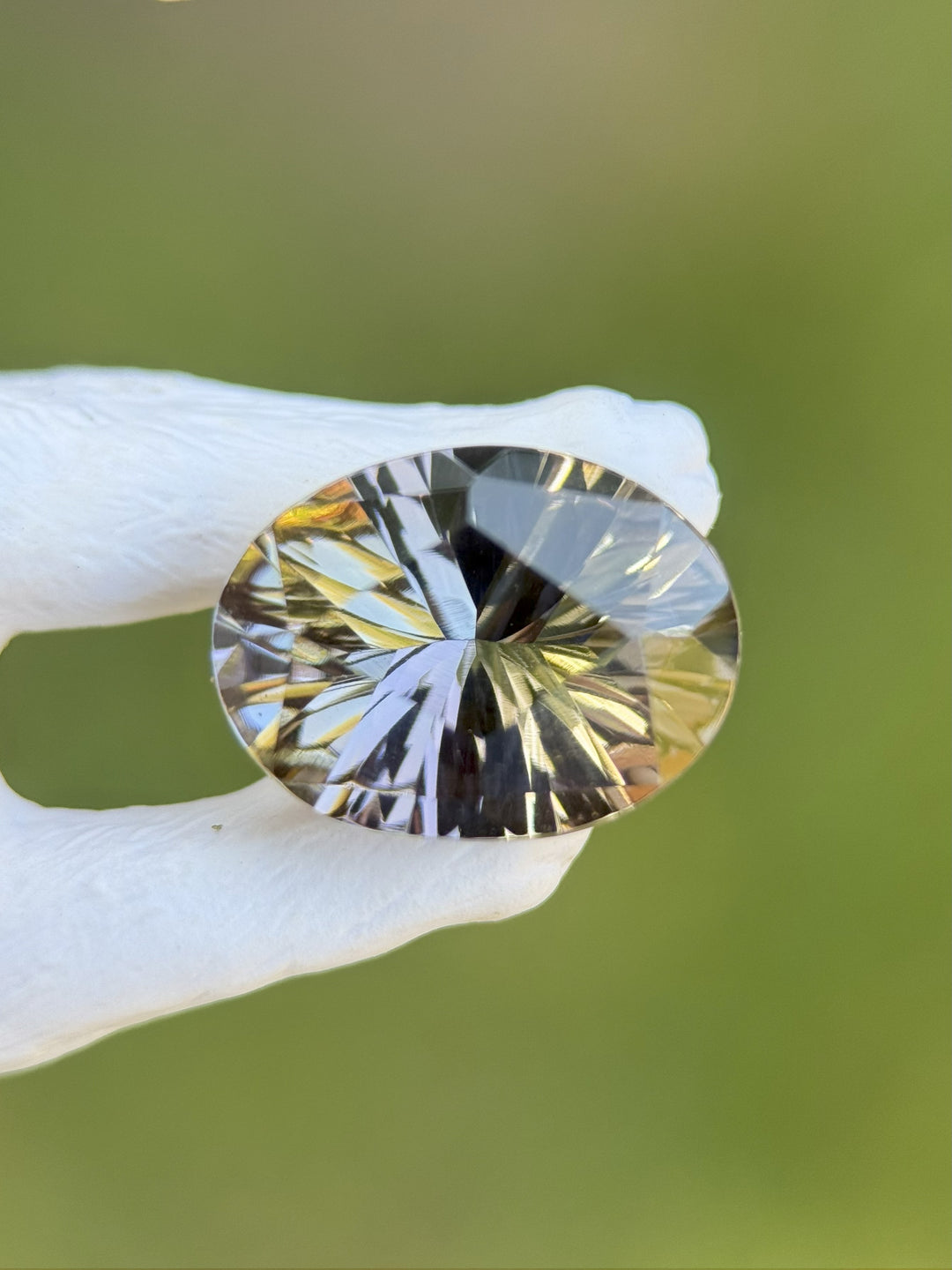 4.78-carat untreated Tanzanite gemstone in custom oval concave cut showing pastel peach, green, and lavender hues, held in gloved hand against a natural background