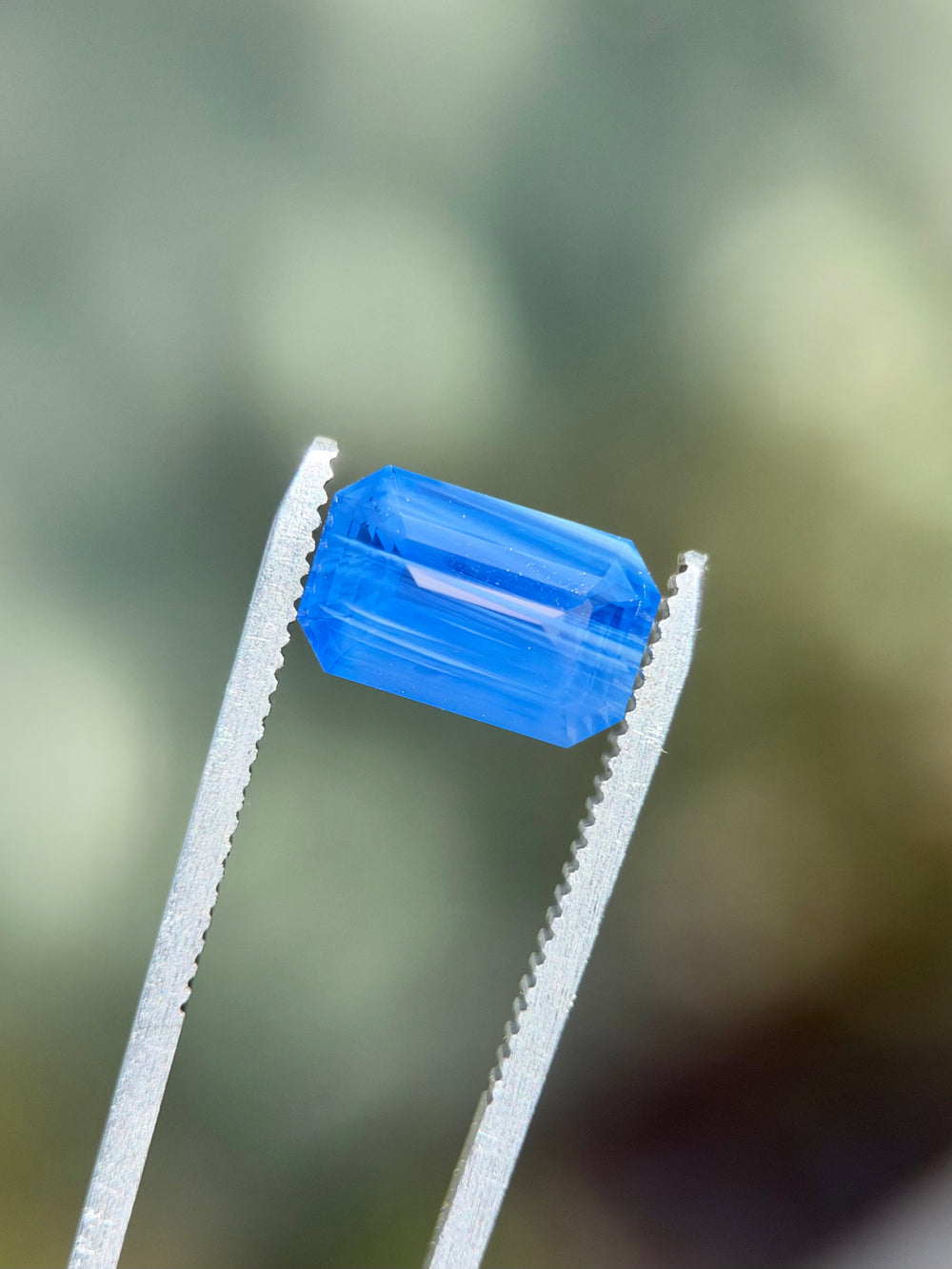Side view of a 5.30 carat Kashmir blue sapphire showing its elongated emerald cut and deep blue banding