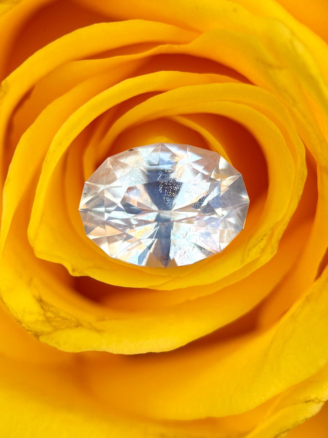 Loose opalescent seafoam off white sapphire oval brilliant cut on yellow background showing soft glow and pastel tones.