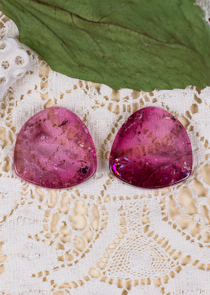 Explore a striking pair of natural deep pink tourmaline slices from Congo, totaling 65.78 carats. Each polished slice measures approximately 25.7 mm across, showcasing saturated raspberry and cranberry-pink coloration, translucent crystal, and distinctive natural inclusions. Their broad silhouettes offer an exceptional canvas for custom statement earrings, contemporary fine jewelry, and artistic gemstone designs.