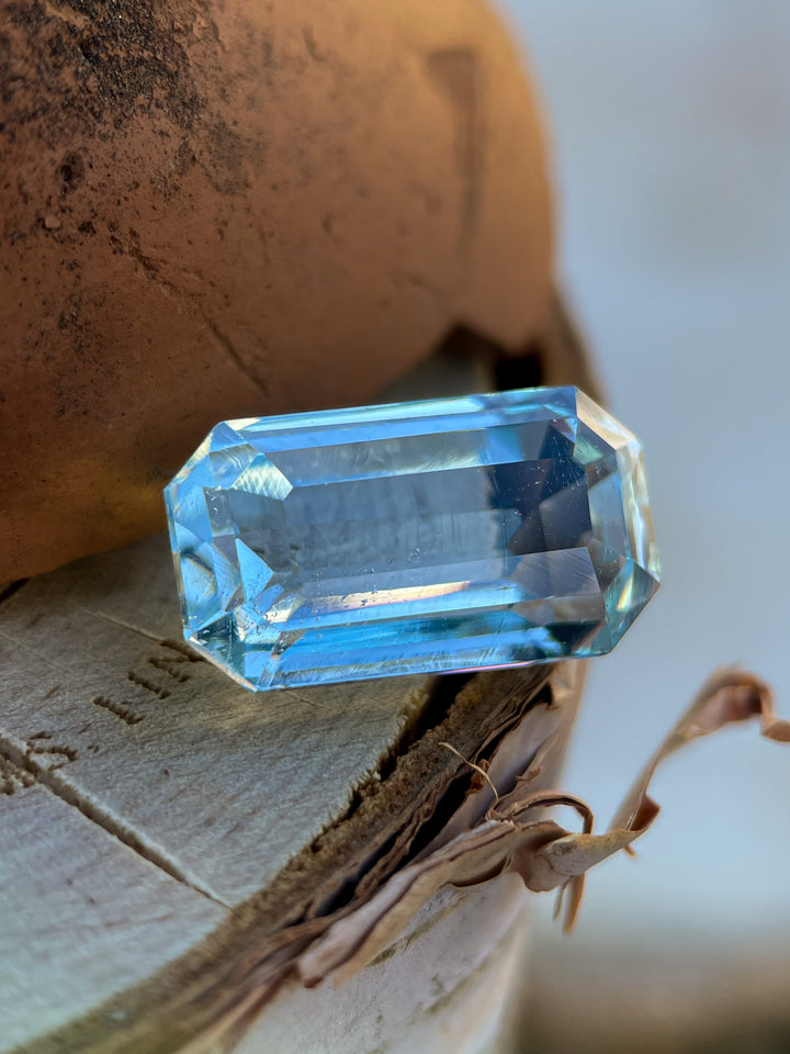 Close-up of an 8.80-carat aquamarine gemstone on a wooden surface, showcasing its mint blue-green brilliance.