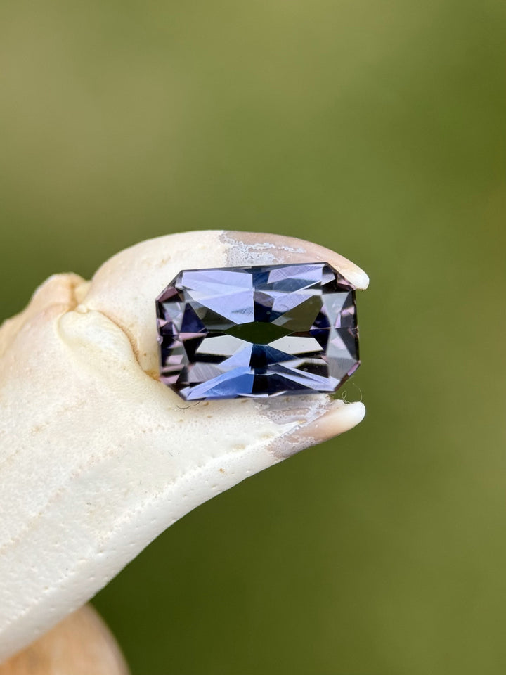 Antique-inspired Tanzanite gem in radiant cut perched on textured claw surface, showcasing multicolor play from Merelani Hills