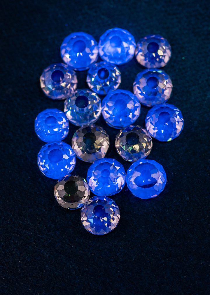 Mughal cut diamond parcel glowing under UV light on blue velvet, revealing light blue fluorescence and antique faceting in fancy light brown diamonds from South Africa